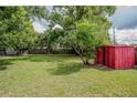 Large backyard with lush greenery, mature trees, and a convenient storage shed at 919 Timor Ave, Orlando, FL 32804