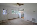 Bright living room featuring a ceiling fan, neutral carpet, and a colorful stained glass front door at 919 Timor Ave, Orlando, FL 32804