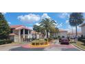 Community entrance featuring a sign, landscaping, gated access, and multiple buildings with red tile roofs at 6294 River Run Pl # 193, Orlando, FL 32807