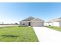Newly constructed tan house with a two-car garage and green lawn at 322 Brennan Ave, Frostproof, FL 33843