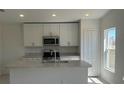 Modern kitchen featuring white cabinets, stainless steel appliances, and an island with a sink at 216 Harper Estates Cir, Lake Wales, FL 33859