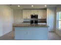 Bright kitchen featuring white cabinets, stainless steel appliances, and a center island with a sink at 221 Harper Estates Cir, Lake Wales, FL 33859