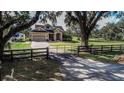 Beautiful single Gathering home with a metal gate, long driveway, and lush green yard at 1004 Country Oaks Ln, Lakeland, FL 33810