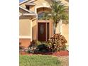 Inviting front entry with a dark wood door and landscaped garden at 1159 Greenley Ave, Groveland, FL 34736