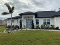 Modern house with gray door, landscaping, and paved driveway at 837 Oaks Shores Rd, Leesburg, FL 34748