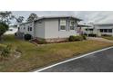 Gray manufactured home with a landscaped yard and American flag at 110 Dogwood Trl, Leesburg, FL 34748