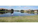 Scenic view of community pond reflecting nearby homes under a bright sky. No swimming allowed at 2802 Quiet Water Trl, Kissimmee, FL 34744