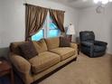 Living room with beige couch, recliner, and patterned curtains at 3376 Se 94Th St, Ocala, FL 34480