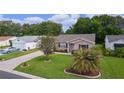 Aerial view of a home with a well-manicured lawn, driveway, and mature landscaping at 1411 Juarez Pl, The Villages, FL 32159