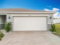 A well-lit two-car garage featuring an extra wide concrete drive and simple landscaping around the base at 2369 Crossandra St, Mascotte, FL 34753
