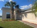Charming one-story home featuring a well-manicured lawn and a welcoming front entrance with a beautiful palm tree at 2410 Shelby Cir, Kissimmee, FL 34743