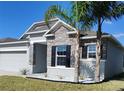 Single-Gathering home featuring stone accents, an attached two car garage and landscaped front yard at 414 Taft Dr, Davenport, FL 33837