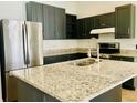 Beautiful kitchen featuring granite countertops, stainless steel appliances, and sleek dark cabinetry at 434 Acacia Tree Way, Kissimmee, FL 34758