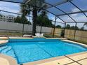 Screened-in pool featuring cool blue water, tile accents, a palm tree and partial fencing at 434 Acacia Tree Way, Kissimmee, FL 34758