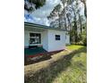 Exterior view of home with sliding door leading to a lushly landscaped yard at 103 Bougainvillea Dr, Leesburg, FL 34748