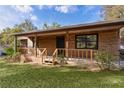 Single-story home boasting a welcoming front porch and natural wood siding, blending seamlessly with the outdoor surroundings at 1107 Linmar Ave, Fruitland Park, FL 34731