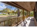 Spacious covered front porch with wood railing, offering an inviting outdoor living space and views of the leafy yard at 1107 Linmar Ave, Fruitland Park, FL 34731
