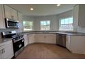 Well-lit kitchen featuring stainless steel appliances, granite countertops, white cabinets, and wood-look tile at 141 W 6Th St, Frostproof, FL 33843