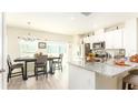 Bright kitchen and dining area featuring stainless steel appliances, granite counters, and wood-look floors at 1412 Mirabella Cir, Davenport, FL 33897