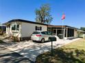 Well-maintained home with a screened-in porch, a spacious driveway, and lush landscaping at 207 Jacaranda Dr, Leesburg, FL 34748