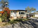 Inviting single-story home adorned with vibrant flowering bushes, lush greenery, and a cozy front porch at 207 Jacaranda Dr, Leesburg, FL 34748