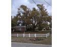 Picturesque backyard featuring a mature tree, complemented by a white picket fence, creating a serene outdoor space at 225 E Cummings St, Lake Alfred, FL 33850