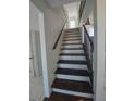 Staircase featuring dark wooden steps and railing, ascending toward a bright landing at 2449 E Lake Dr, Deland, FL 32724