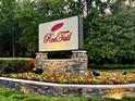 Stone RedTail community sign surrounded by colorful flowers and lush greenery welcomes residents and guests at 25879 Crossings Bluff Ln, Sorrento, FL 32776