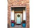 Inviting entryway with a light blue front door, flanked by stone accents and beautiful potted plants at 25879 Crossings Bluff Ln, Sorrento, FL 32776