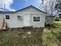 Exterior view of the home, showcasing the white siding, small windows, door and air conditioner at 309 Old Mission Rd, New Smyrna Beach, FL 32168