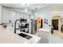 Updated kitchen with stainless steel appliances, white cabinetry, and stylish fixtures, leading to laundry area at 402 Bramble Way, Minneola, FL 34715