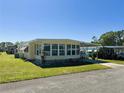 Inviting exterior view of a well-kept mobile home with lush lawn and a convenient carport at 114 Caladium St, Leesburg, FL 34748