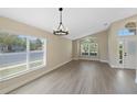Bright living room with hardwood floors, a modern light fixture, and arched windows allowing natural light at 9324 Pecky Cypress Way, Orlando, FL 32836