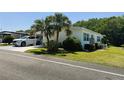 Well-maintained single-story home featuring a carport, landscaped yard with mature trees, and fresh green grass at 106 Palo Verde Dr, Leesburg, FL 34748