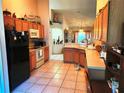 Open kitchen showing tile flooring, wood cabinets, and black appliances at 4613 Eaglet Ln, Kissimmee, FL 34746