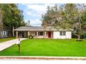 Charming single-story home features a bright red front door, brick column accents and a lush green lawn at 727 Se 12Th St, Ocala, FL 34471
