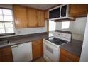 Well-lit kitchen featuring white appliances, wooden cabinets, and views to living area at 1000 S Semoran Blvd # 306, Winter Park, FL 32792