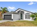 Single-story home with gray roof, two-car garage, and a manicured lawn at 11172 Pinewood Cove Ln, Orlando, FL 32817