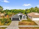 Aerial view of single-story home with grey roof, a two-car garage, and lush green surroundings at 11172 Pinewood Cove Ln, Orlando, FL 32817