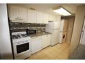 Bright kitchen featuring white appliances and cabinets, with tile backsplash at 125 Water Front Way # 200, Altamonte Springs, FL 32701