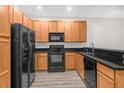 Modern kitchen with black appliances, warm wood cabinets, and sleek black countertops at 1880 Garden Sage Dr, Oviedo, FL 32765