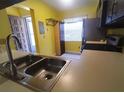 This kitchen boasts a double basin sink and yellow walls, with a window that adds brightness at 3475 Flossmoor Ave # 103, Orlando, FL 32822