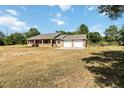 Inviting brick home featuring a two-car garage and a covered porch, set on a spacious lawn under a bright sky at 5155 Holopaw Rd, St Cloud, FL 34773