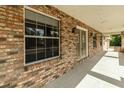 Close-up of a brick porch with large windows and a wooden door, showcasing architectural details and natural light at 5155 Holopaw Rd, St Cloud, FL 34773