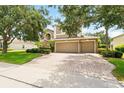 Exterior showcasing a three-car garage, brick driveway, and mature trees enhancing curb appeal at 1085 Harmony Ln, Clermont, FL 34711