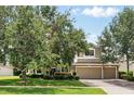 Exterior showcasing a three-car garage, brick driveway, and mature trees enhancing curb appeal at 1085 Harmony Ln, Clermont, FL 34711