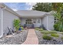 Inviting front porch area with seating, landscaping, and a brick pathway leading to the entrance at 1305 Guerra Ave, The Villages, FL 32159