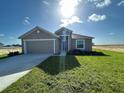 A single-Gathering home with a two-car garage, green lawn, and minimal landscaping in a sunny, open setting at 2117 Emma Ln, Lake Wales, FL 33898