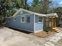Side view of light blue home with a small wooden porch and fresh landscaping at 2217 Azalea Ct, Lakeland, FL 33815