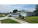 Single-story home with attached two-car garage, sidewalk, and adjacent green space at 303 Silk Oak Dr, Kissimmee, FL 34743